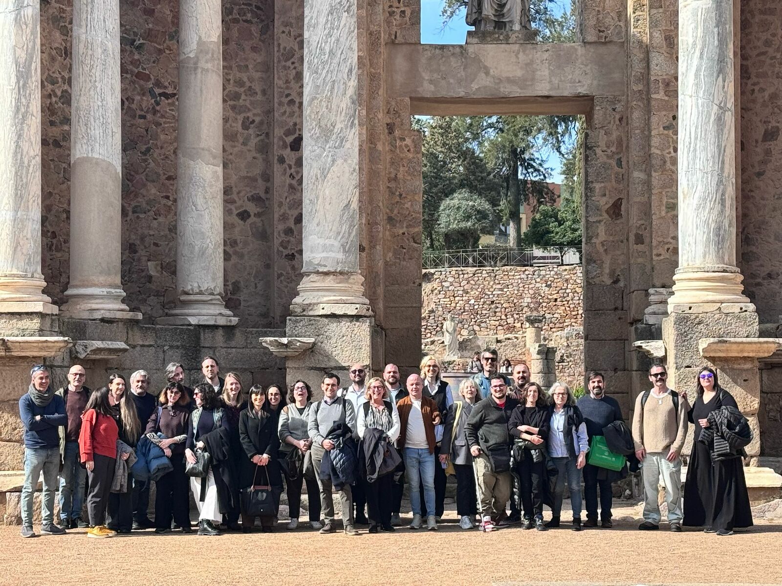 Group photo of the partners of the EU project WE WANT MORE in Spain, in front of an ancient columned building. 25 people, different clothing.